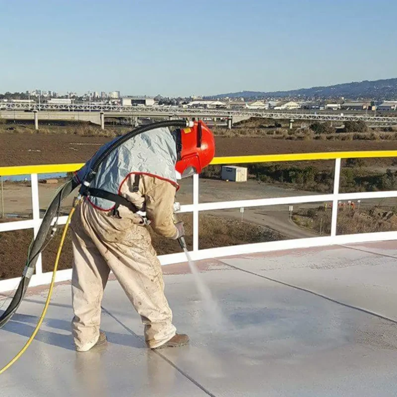 A painting and coating specialist performing surface preparation on a container roof, wearing ventilation PPE gear